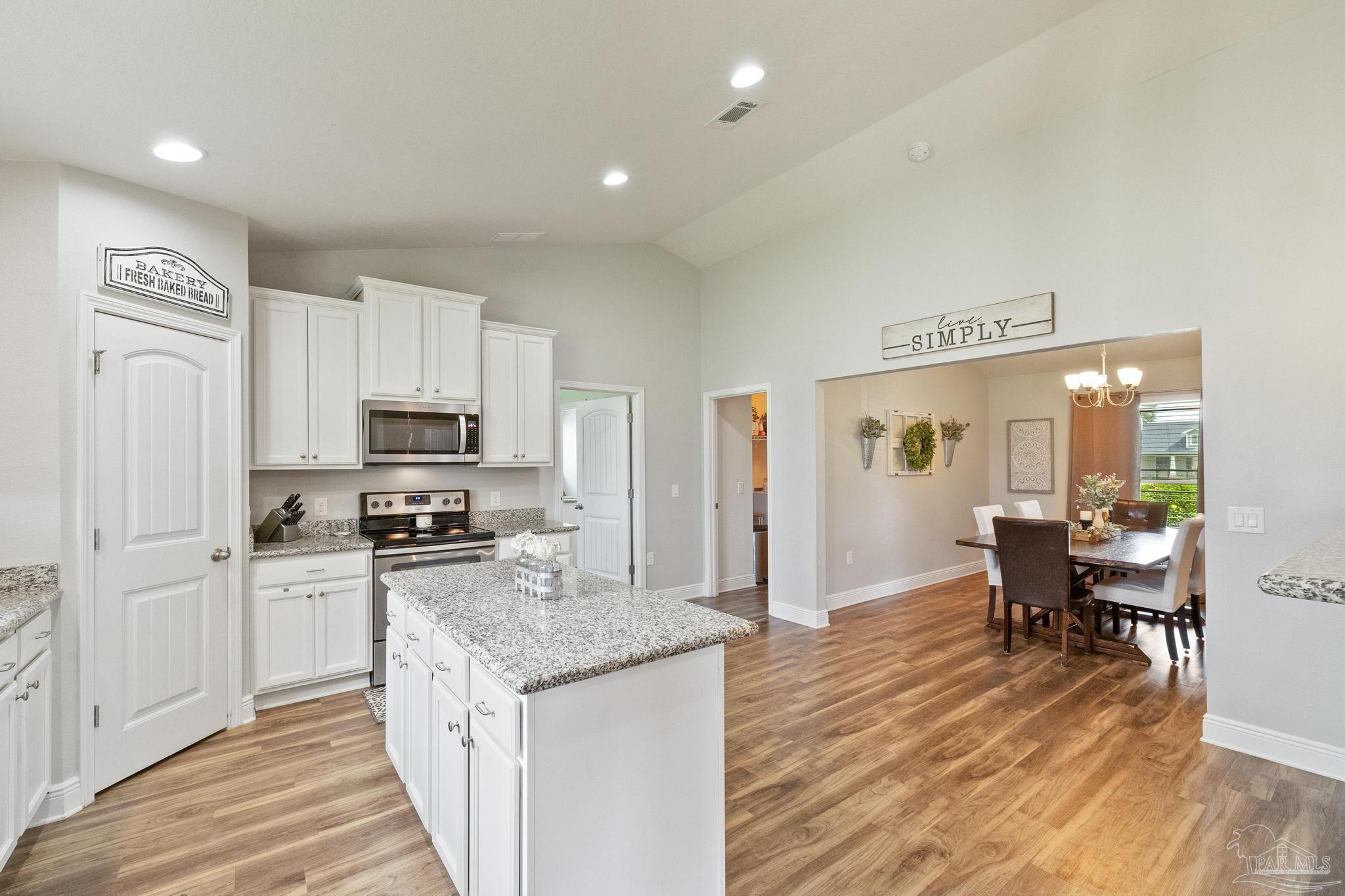 4037 Millwright Way Pace, FL 32571 - Photo 25 of 46 a kitchen with granite countertop a stove a sink a refrigerator and white cabinets with wooden floor