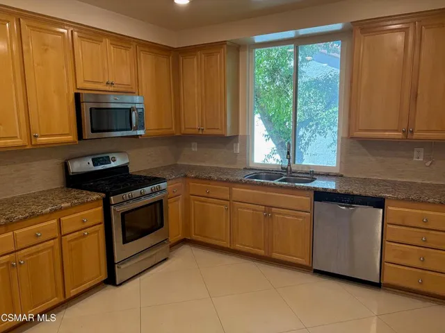 a kitchen with stainless steel appliances granite countertop a refrigerator stove and microwave