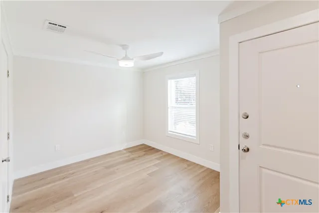 an empty room with wooden floor and windows