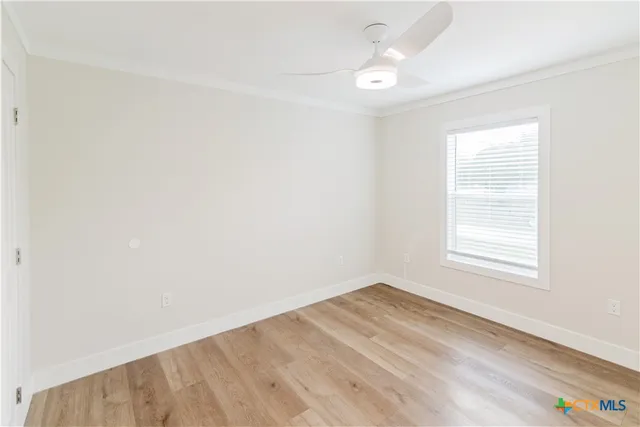 an empty room with wooden floor chandelier fan and windows