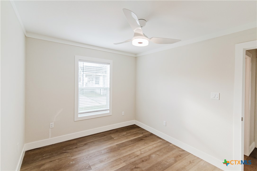 404 Bridge Street Cuero, TX 77954 - Photo 21 of 40 an empty room with wooden floor chandelier fan and windows