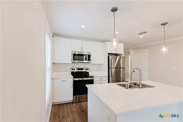 a kitchen with stainless steel appliances a refrigerator a sink a stove a microwave and island