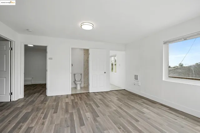 a view of an empty room with wooden floor and closet