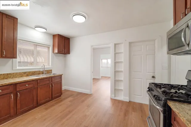a view of a kitchen with a sink stove cabinets and empty room