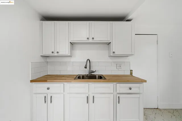a kitchen with white cabinets and sink