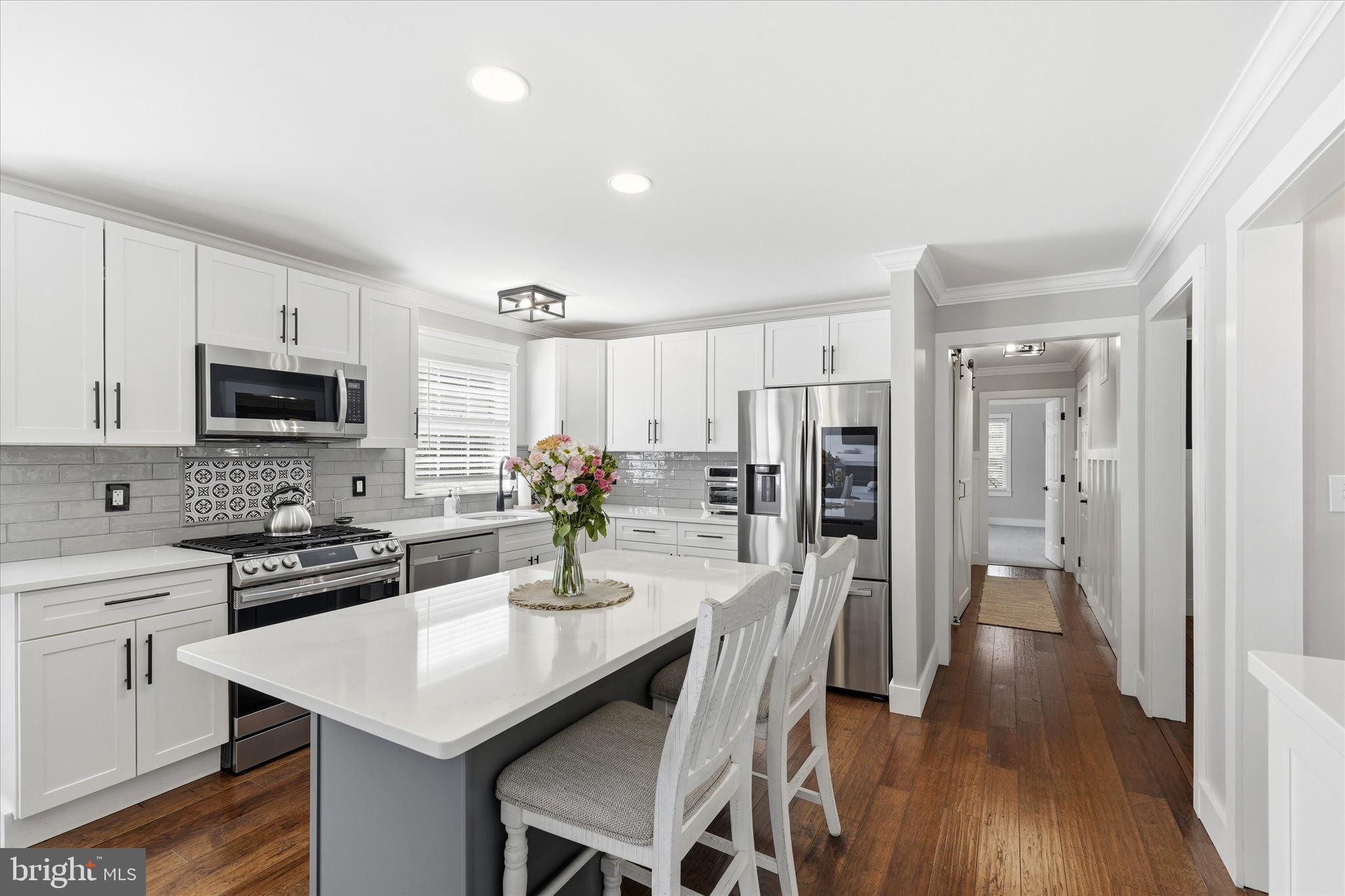 176 Warren Grove Road Barnegat, NJ 08005 - Photo 23 of 71 a kitchen with stainless steel appliances kitchen island granite countertop a refrigerator a stove a sink a dining table and chairs with wooden floor