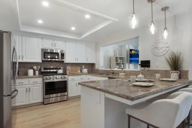a kitchen with kitchen island granite countertop a sink cabinets and stainless steel appliances