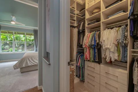 a view of walk in closet with clothes and shoes
