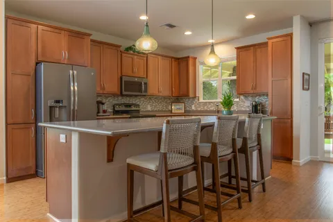 a kitchen with kitchen island granite countertop a table chairs microwave and refrigerator