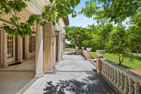 a view of a pathway of a house with large trees and wooden fence