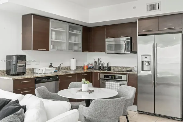 a kitchen with stainless steel appliances granite countertop a stove a sink a microwave refrigerator and dining table