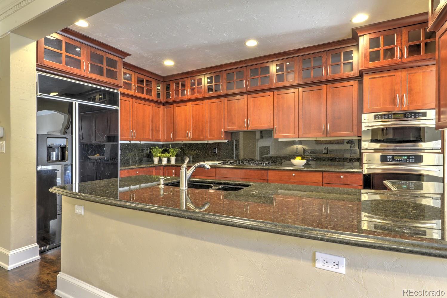 490 Columbine Street Denver, CO 80206 - Photo 20 of 33 a kitchen with stainless steel appliances granite countertop a refrigerator a stove and a sink with wooden cabinets