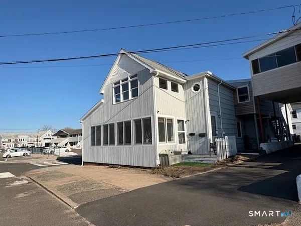 a view of a white building among the street with parked cars