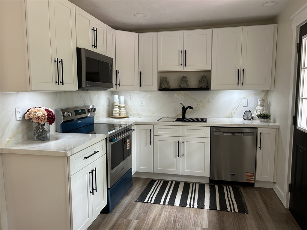 61 Esta Road Plymouth, MA 02360 - Photo 14 of 40 a kitchen with white cabinets a sink dishwasher and a stove with wooden floor