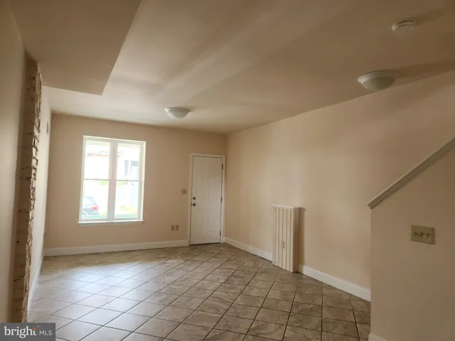 a view of an empty room with window and chandelier fan