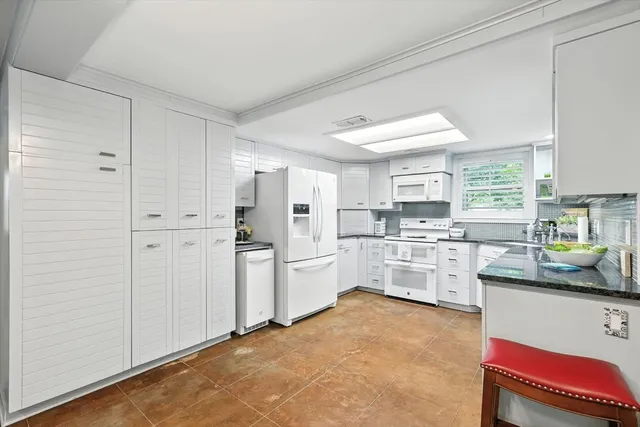 a kitchen with white cabinets and white appliances