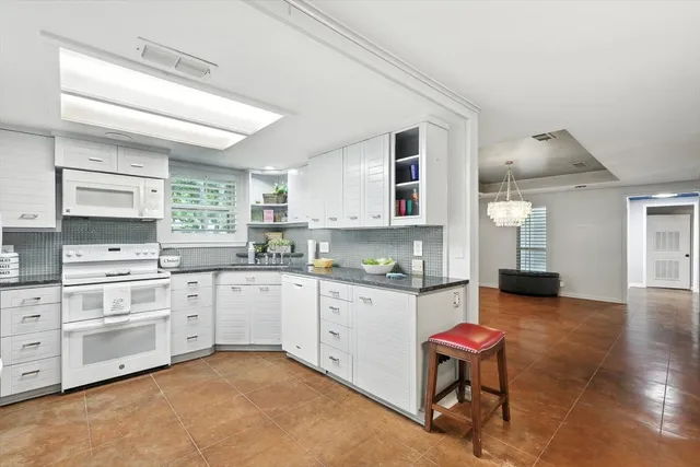 a kitchen with a stove a sink and white cabinets