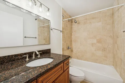 a bathroom with a granite countertop sink toilet mirror and shower