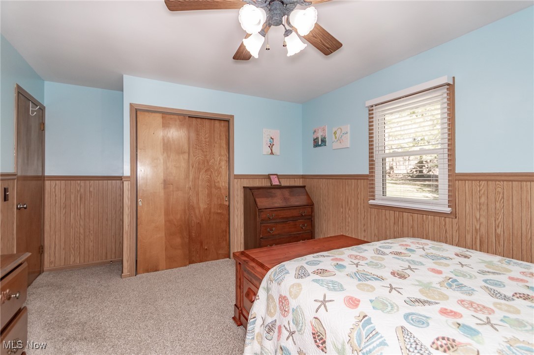 10495 Mulberry Road Chardon, OH 44024 - Photo 35 of 48 Carpeted bedroom with a wainscoted wall, wooden walls, a closet, and ceiling fan
