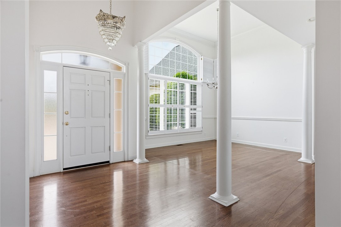 This bright entrance foyer welcomes with architectural columns and gleaming hardwood floors.