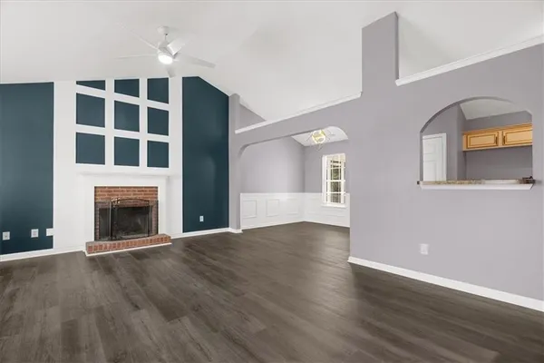 a view of an empty room with wooden floor and a fireplace