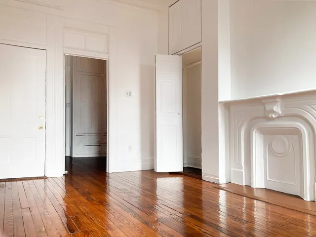 an empty room with wooden floor and mirror