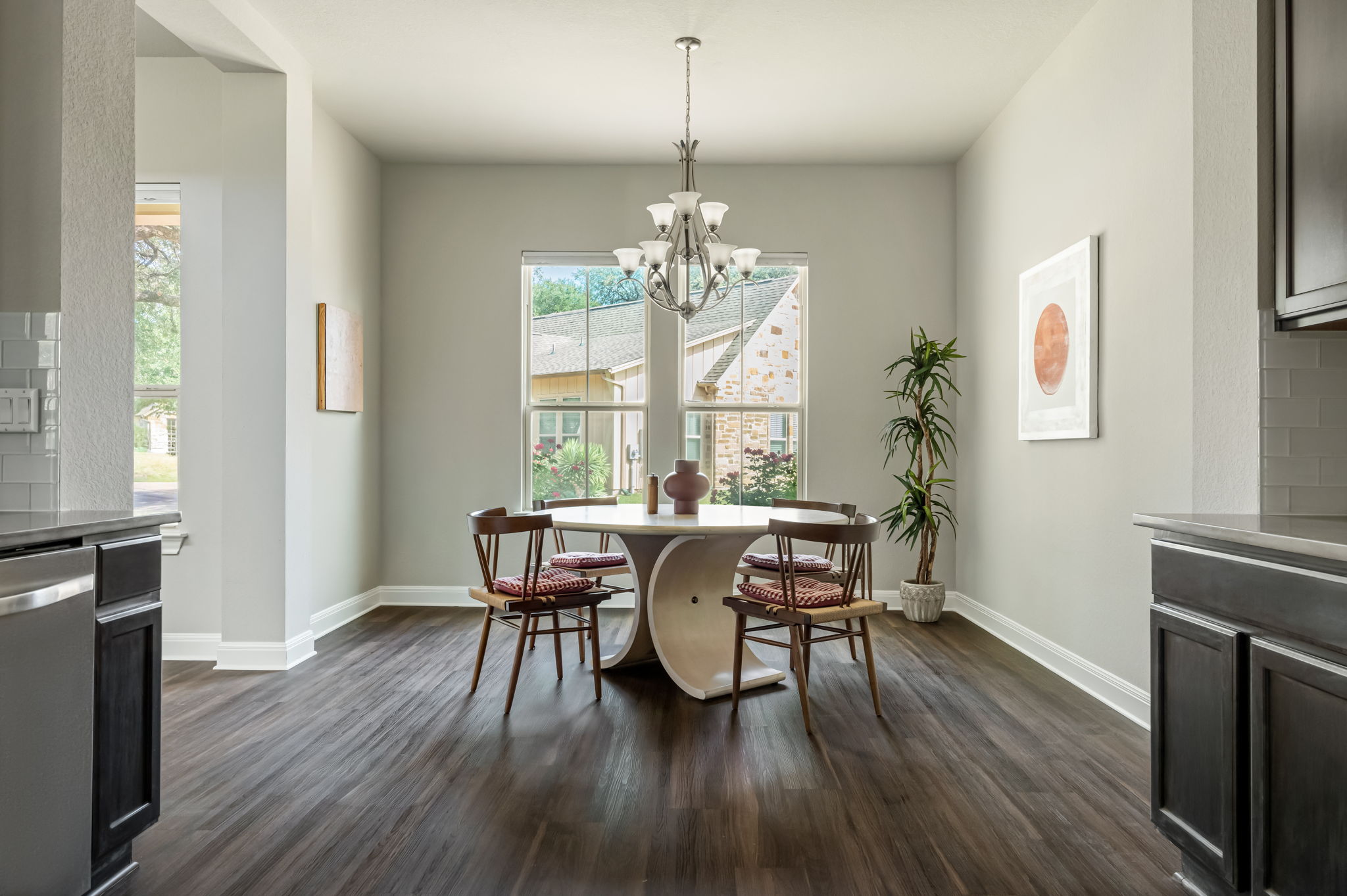 2516 Hopsack Mills Road Austin, TX 78748 - Photo 9 of 39 Dining area featuring a contemporary chandelier, two large windows, dark wood-finish flooring, and light-toned walls