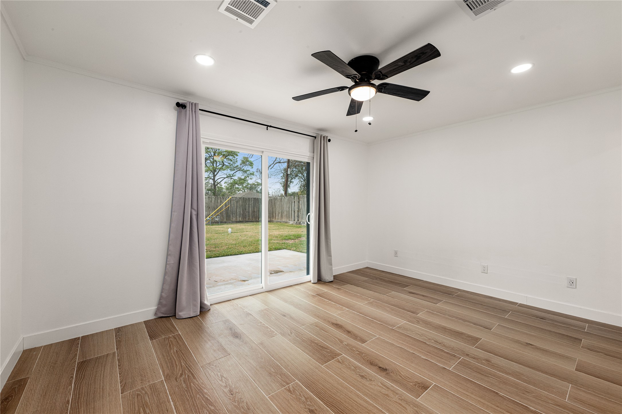 3410 Tanglewilde Street Houston, TX 77063 - Photo 11 of 17 an empty room with wooden floor fan and windows