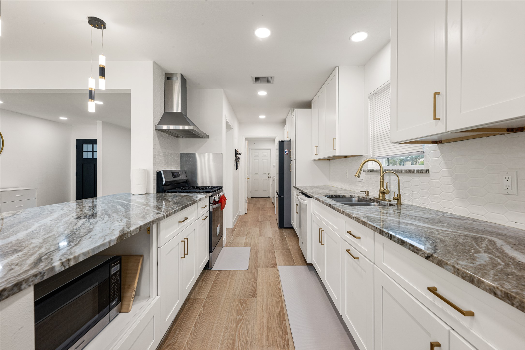 3410 Tanglewilde Street Houston, TX 77063 - Photo 8 of 17 a large kitchen with stainless steel appliances granite countertop a lot of counter space and wooden floor