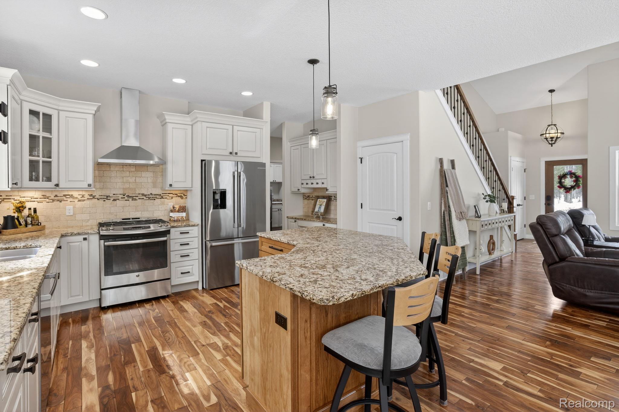 101 Highview Road Traverse City, MI 49696 - Photo 86 of 88 Kitchen with stainless steel appliances, open floor plan, light stone counters, two tone cabinets, and glass insert cabinets