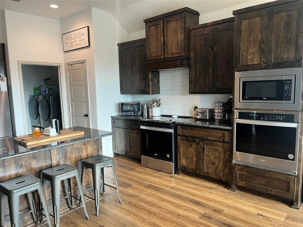 108 Wiley Stephenville, TX 76401 - Photo 21 of 25 a kitchen with granite countertop a stove top oven a sink dishwasher and wooden cabinets with wooden floor