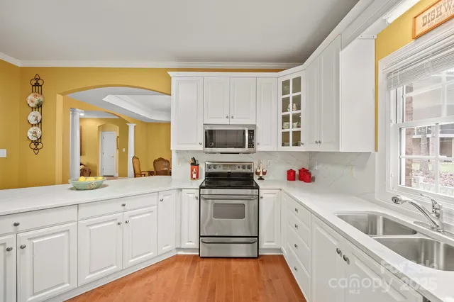 a kitchen with granite countertop a sink cabinets stainless steel appliances and a window