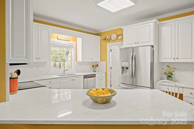 a kitchen with stainless steel appliances granite countertop a refrigerator sink and white cabinets