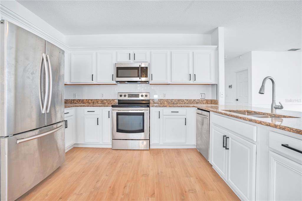 444 Acacia Tree Way Kissimmee, FL 34758 - Photo 11 of 38 a kitchen with stainless steel appliances granite countertop white cabinets a sink a stove a refrigerator and a microwave