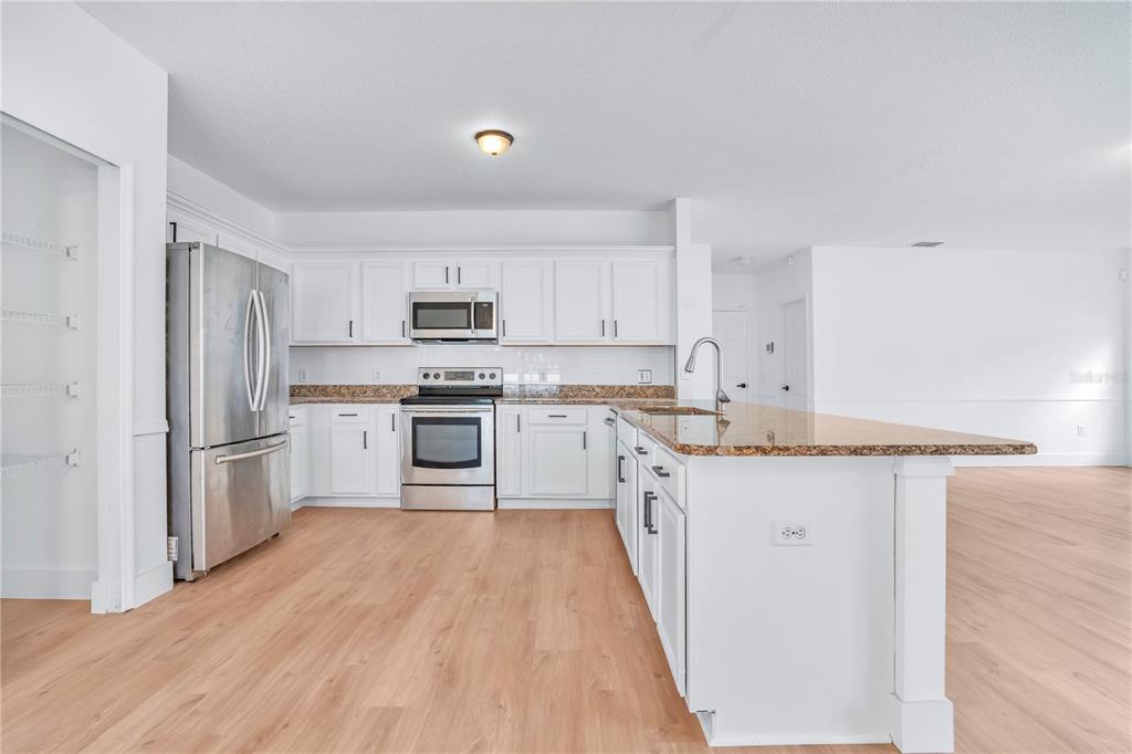 444 Acacia Tree Way Kissimmee, FL 34758 - Photo 9 of 38 a kitchen with granite countertop white cabinets and stainless steel appliances