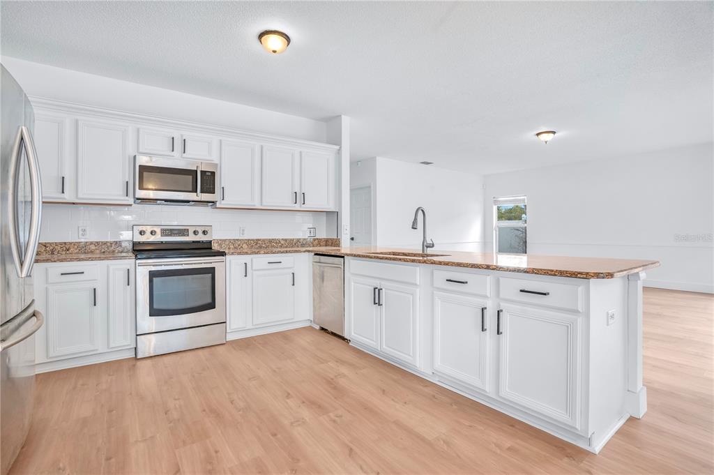 444 Acacia Tree Way Kissimmee, FL 34758 - Photo 10 of 38 a kitchen with granite countertop white cabinets and stainless steel appliances