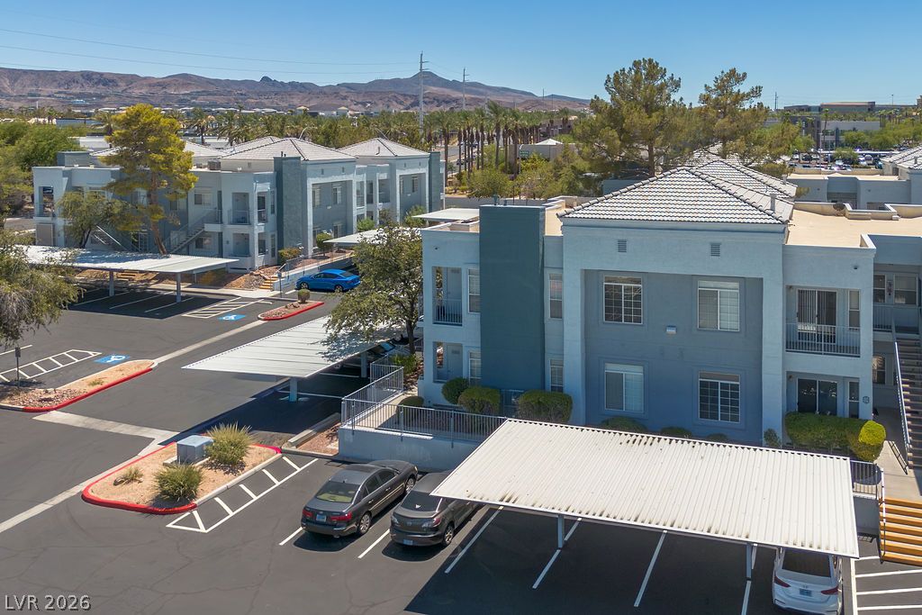 2201 Ramsgate Drive, Unit 514 Henderson, NV 89074 - Photo 25 of 28 Contemporary apartment buildings offer convenient covered parking amidst desert landscaping, with distant mountains providing a scenic backdrop.