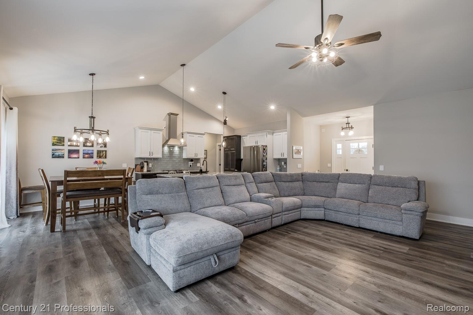 4914 TORATOLA Lane Howell, MI 48843 - Photo 11 of 39 Living area featuring hanging lights, a high ceiling, dark wood-style flooring, and a ceiling fan