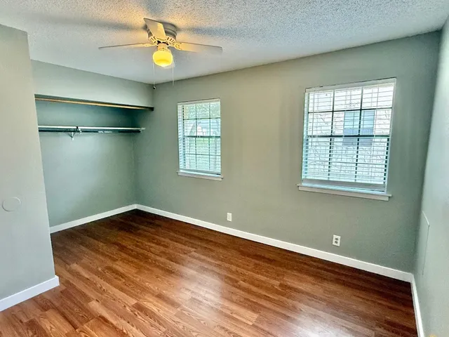 a view of an empty room with a window and wooden floor