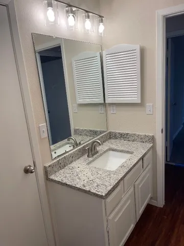 a bathroom with a granite countertop sink and a mirror