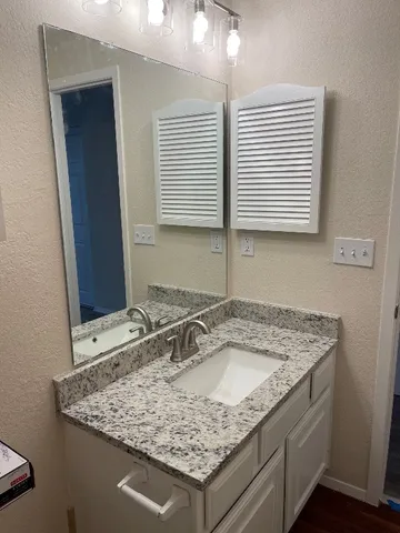 a bathroom with a granite countertop sink and a mirror