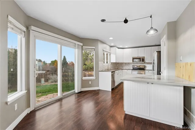 a open kitchen with stainless steel appliances granite countertop a refrigerator a sink dishwasher a stove and white countertops with wooden floor