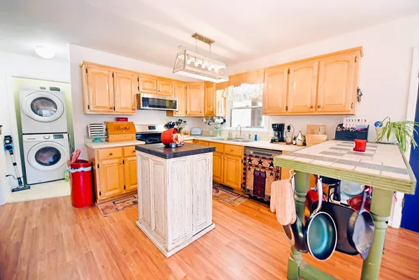 a utility room with stainless steel appliances lots of clutter and cabinets