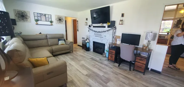 a living room with furniture a fireplace a flat screen tv and a window