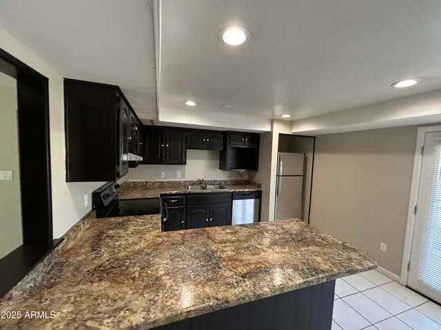a large kitchen with kitchen island granite countertop a refrigerator and a sink