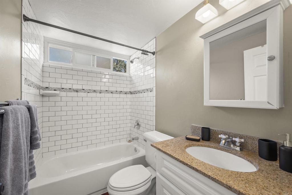 3099 Driscoll Drive San Diego, CA 92117 - Photo 30 of 41 a bathroom with a granite countertop sink toilet mirror and bathtub