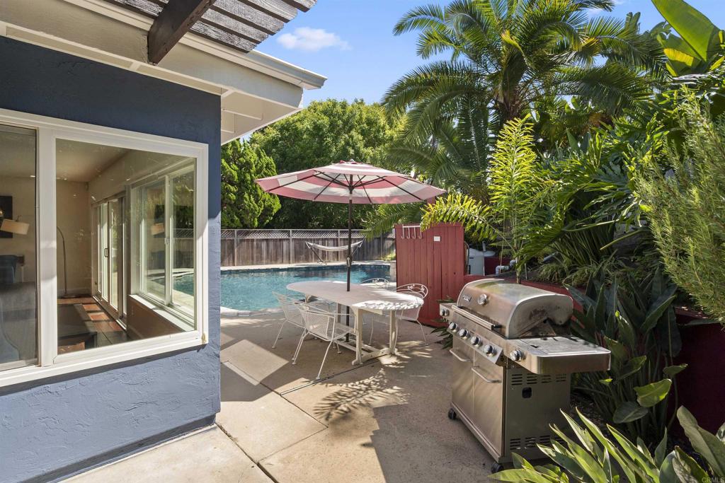 3099 Driscoll Drive San Diego, CA 92117 - Photo 37 of 41 a view of a patio with table and chairs under an umbrella with a fire pit