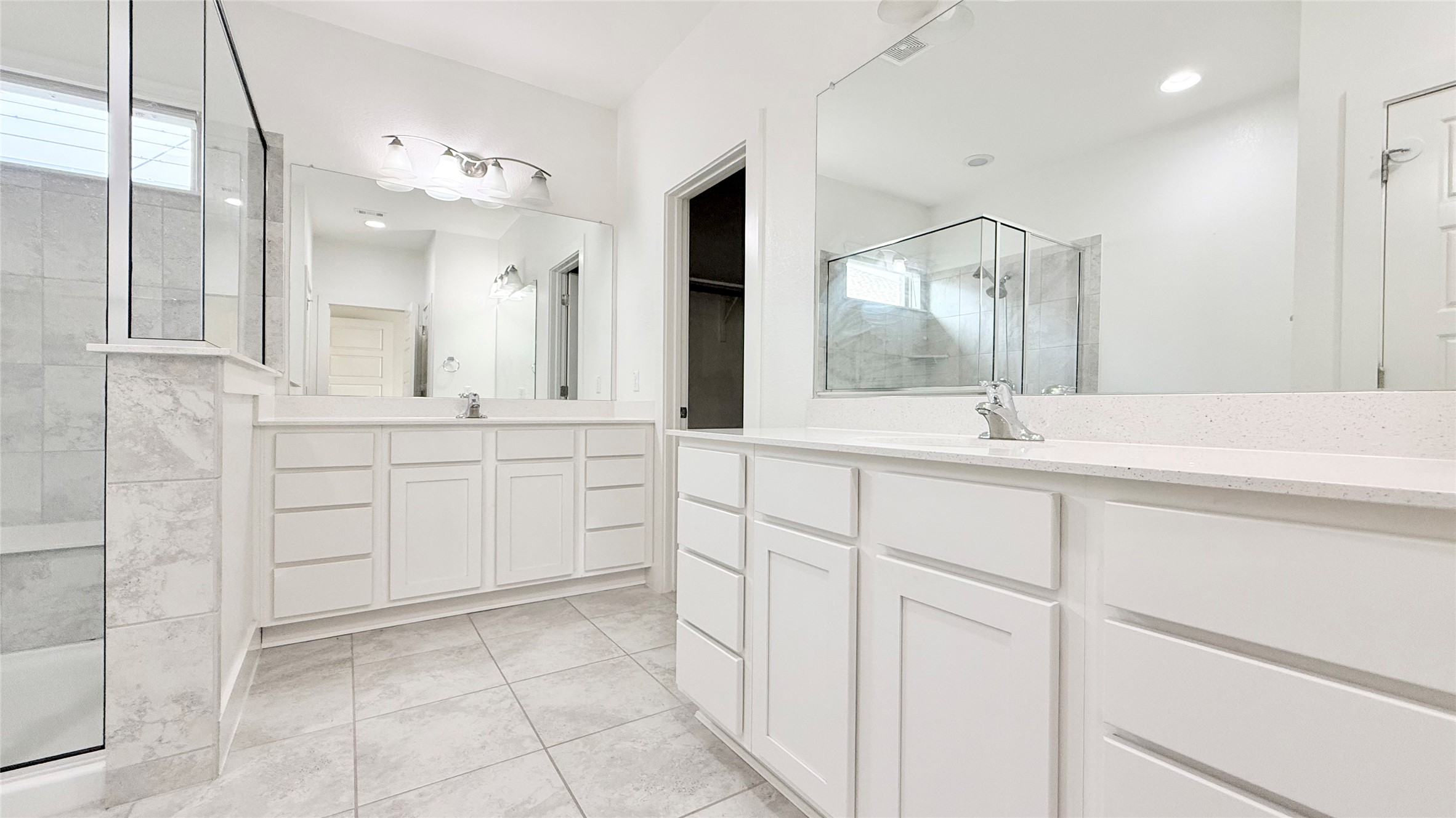 600 Golden Glory Road Leander, TX 78641 - Photo 13 of 21 Bathroom with a stall shower, two vanities, light tile patterned flooring, and plenty of natural light