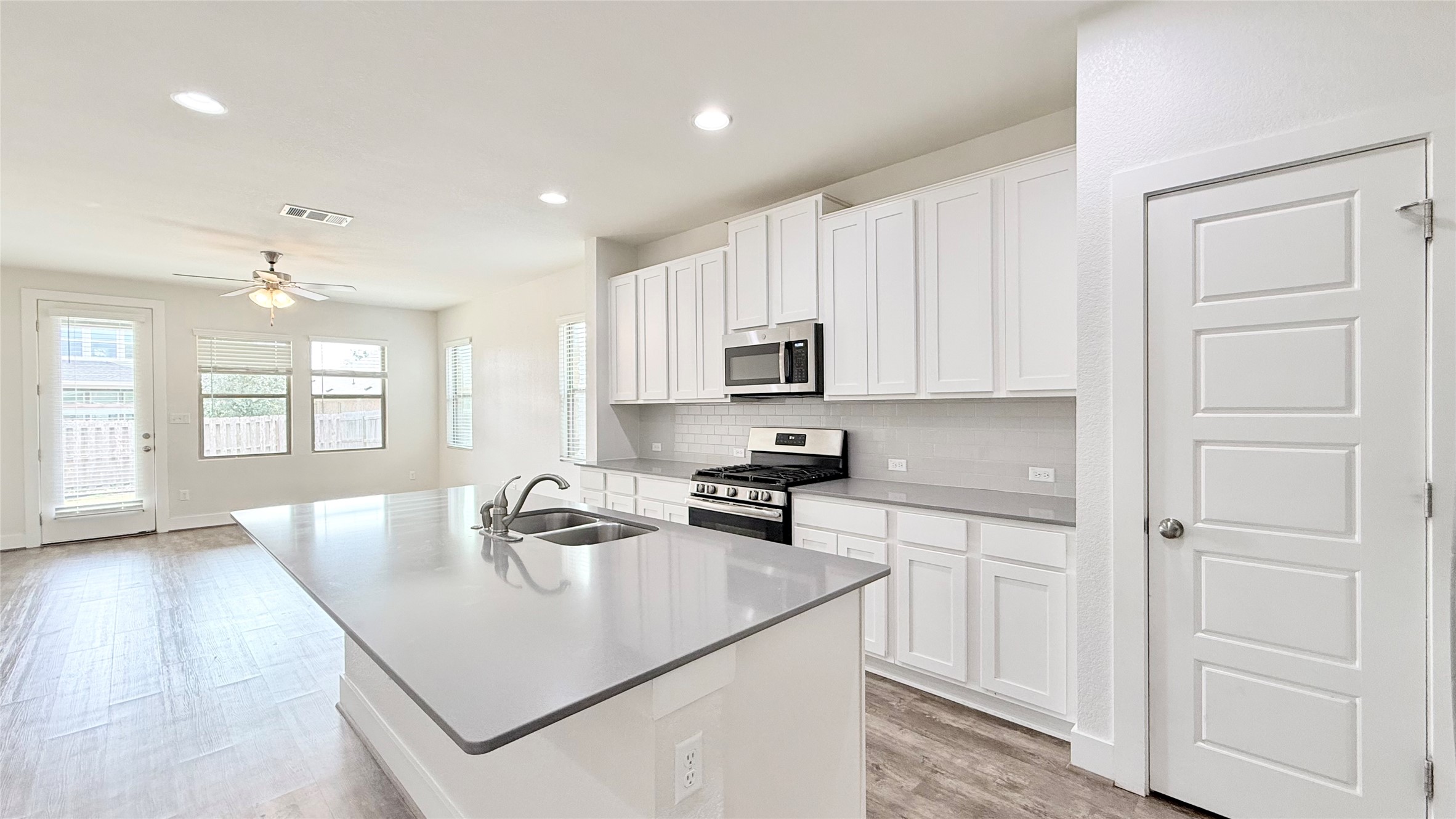 600 Golden Glory Road Leander, TX 78641 - Photo 5 of 21 Kitchen featuring stainless steel appliances, light wood-type flooring, a kitchen island with sink, white cabinetry, and ceiling fan