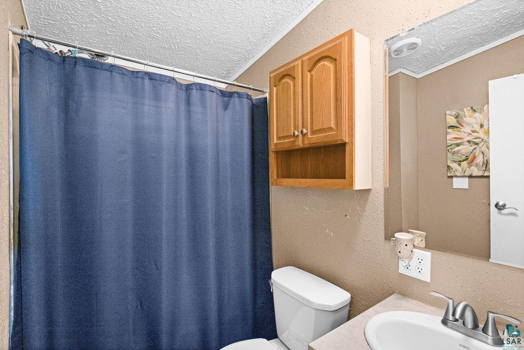 6638 Tabako Road Wright, MN 55798 - Photo 14 of 34 Full bath with a textured wall, a textured ceiling, vanity, and a shower with shower curtain